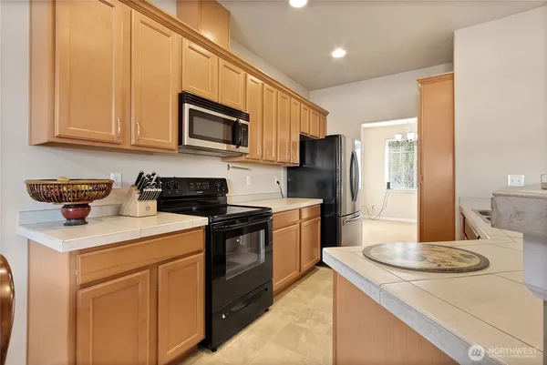 a kitchen with stainless steel appliances granite countertop a sink a stove a refrigerator a washer and dryer