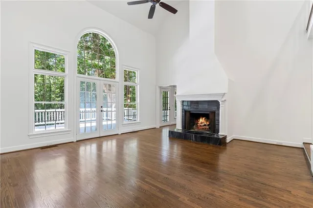 an empty room with chandelier fan and windows