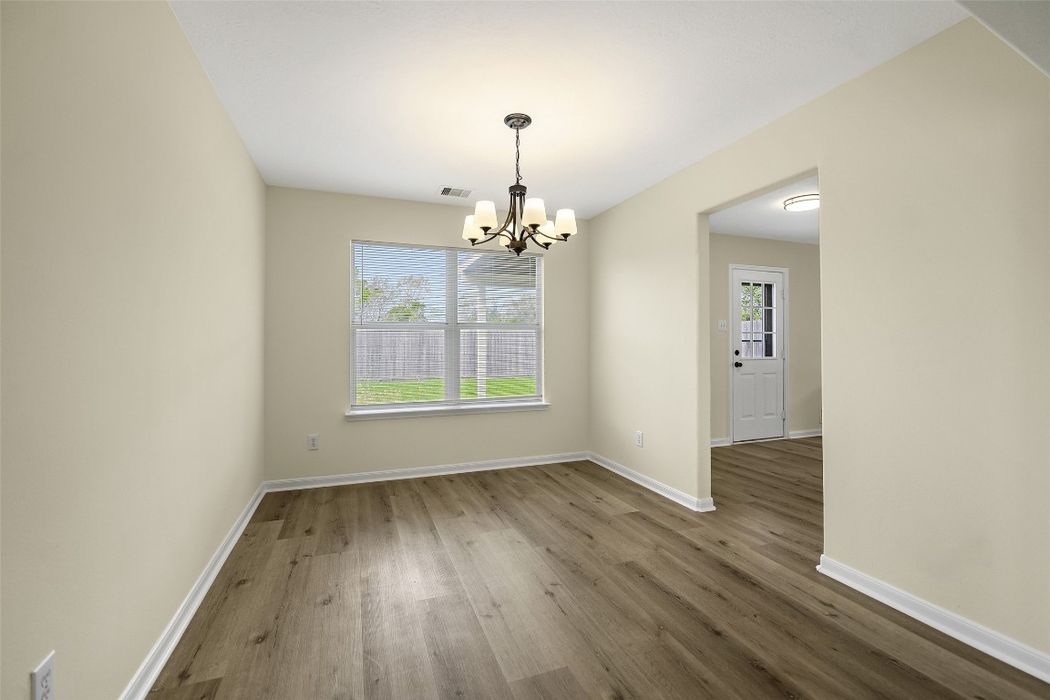 13226 Ridgewood Knoll Lane Houston, TX 77047 - Photo 16 of 37 an empty room with wooden floor chandelier and windows