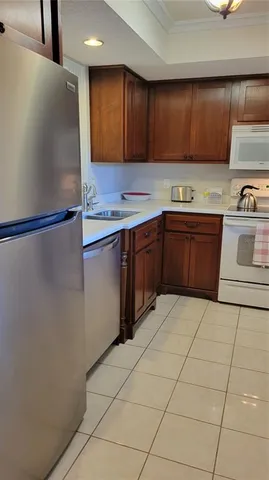 a kitchen with stainless steel appliances granite countertop a refrigerator a stove and a sink with wooden cabinets