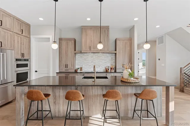 a kitchen with stainless steel appliances granite countertop a sink a stove and a wooden floor