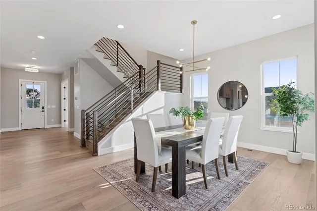 a dining room with kitchen island stainless steel appliances furniture large window and wooden floor