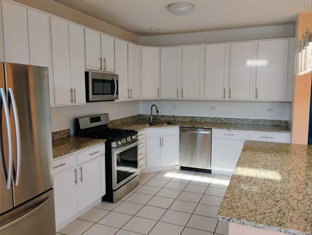 a kitchen with granite countertop white cabinets stainless steel appliances and a counter space