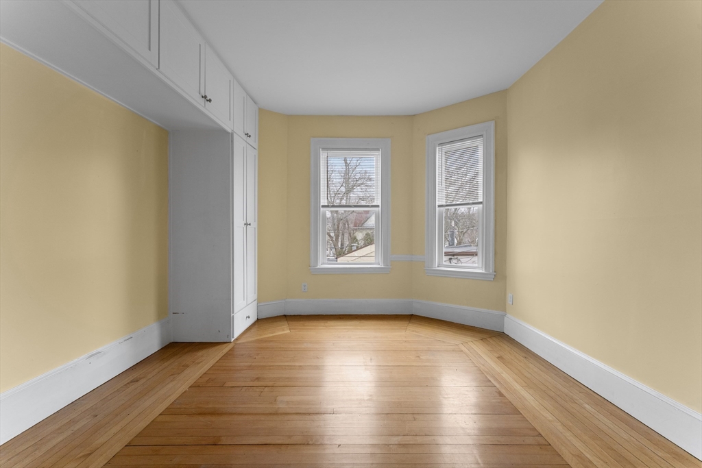571 Washington Street, Unit 1 Boston, MA 02135 - Photo 5 of 13 a view of empty room with wooden floor and fan