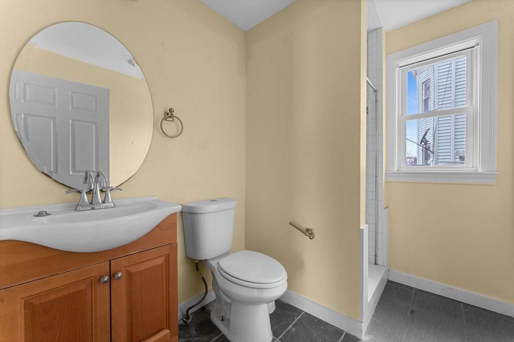 571 Washington Street, Unit 1 Boston, MA 02135 - Photo 8 of 13 a bathroom with a toilet sink and mirror
