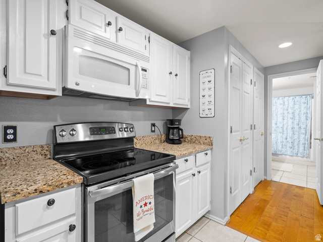900 Bitner Road, Unit D 34 Park City, UT 84098 - Photo 11 of 25 Kitchen featuring stainless steel range with electric stovetop, light tile patterned floors, white microwave, white cabinets, and recessed lighting