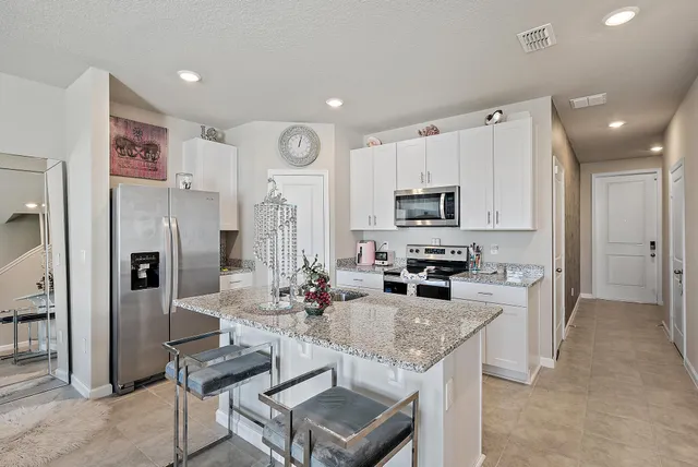 a kitchen with stainless steel appliances granite countertop a refrigerator a stove a sink a dining table and chairs