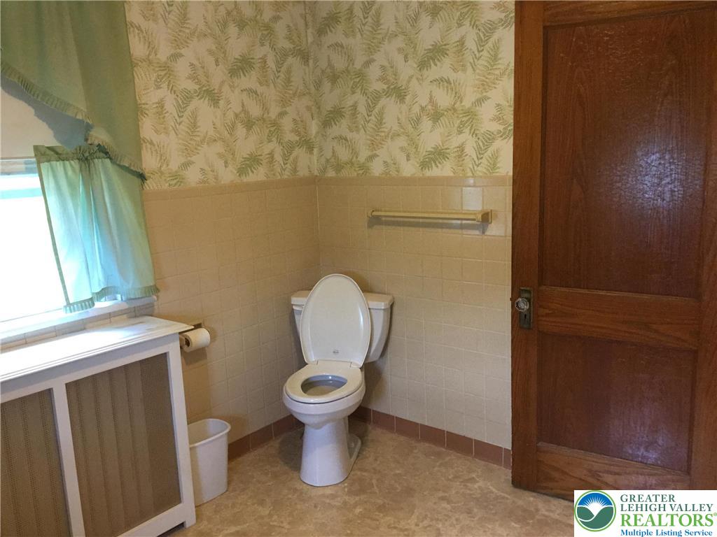1105 Main Street Slatington, PA 18080 - Photo 16 of 31 A well-lit bathroom features classic tile and wood paneling, offering a functional and enduring design.
