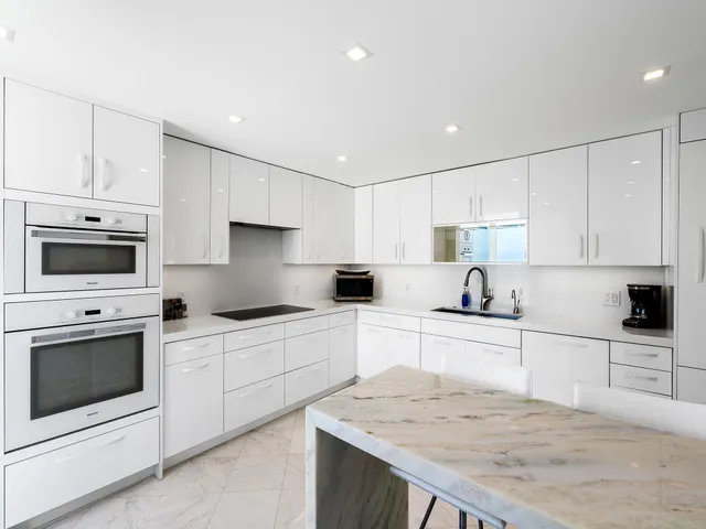a large white kitchen with a large window and refrigerator