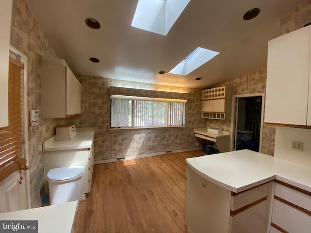 8201 Scotts Level Road Pikesville, MD 21208 - Photo 8 of 31 a kitchen with a sink a toilet and wooden floor