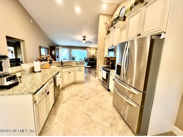 a kitchen with stainless steel appliances granite countertop a refrigerator a stove a sink and a dining table