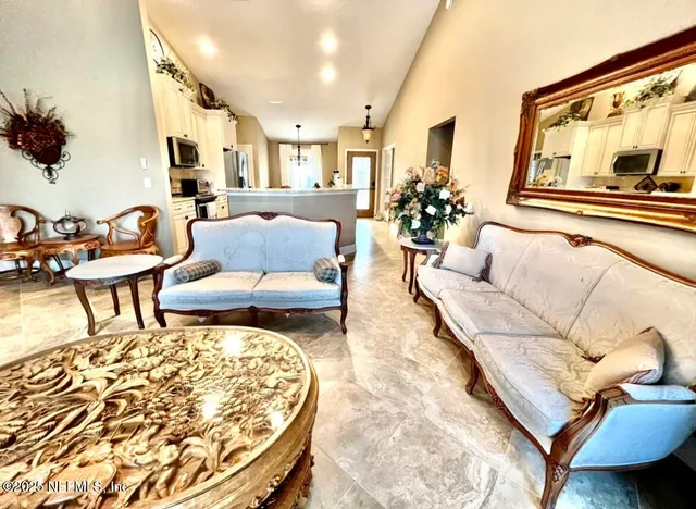 a living room with furniture and a large mirror next to a window