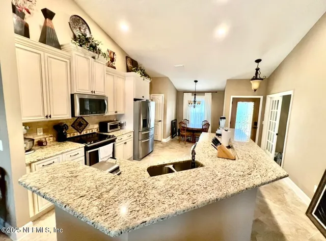 a kitchen with stainless steel appliances granite countertop a sink refrigerator stove and microwave