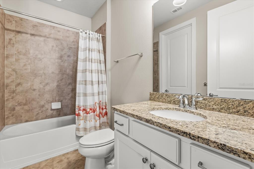 10713 BERRY CREEK Road Orlando, FL 32836 - Photo 28 of 60 a bathroom with a granite countertop sink a toilet a mirror a bathtub and shower