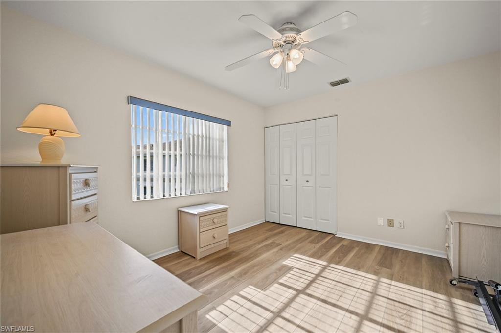 249 Gabriel Circle, Unit 12 Naples, FL 34104 - Photo 20 of 40 a bedroom with a bed and a chandelier