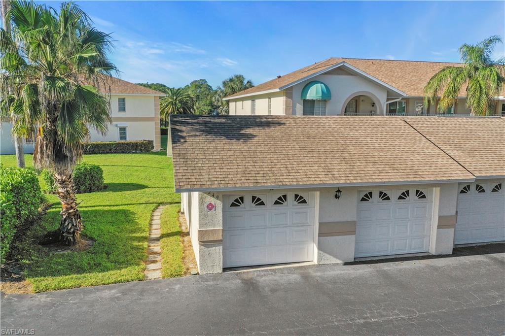 249 Gabriel Circle, Unit 12 Naples, FL 34104 - Photo 26 of 40 a front view of a house with a yard and garage
