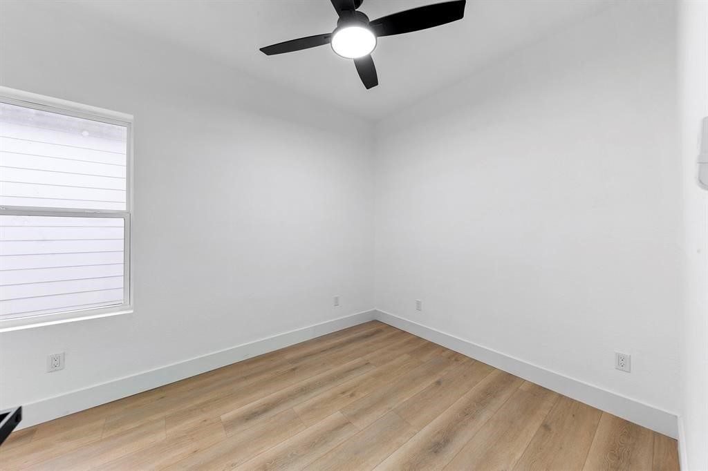 2805 Nettleton Street Houston, TX 77004 - Photo 8 of 9 This is a bright, minimalist room with white walls and light wood flooring. It features a ceiling fan with a light, and a single window allowing natural light to enter. Ideal for a bedroom or office space.