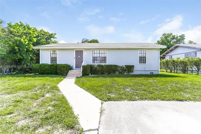 a view of a house with a yard and potted plants