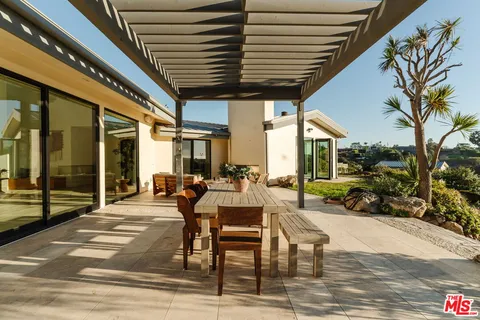 a view of a patio with table and chairs potted plants with floor to ceiling window