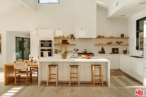 a kitchen with stainless steel appliances a table and chairs in it