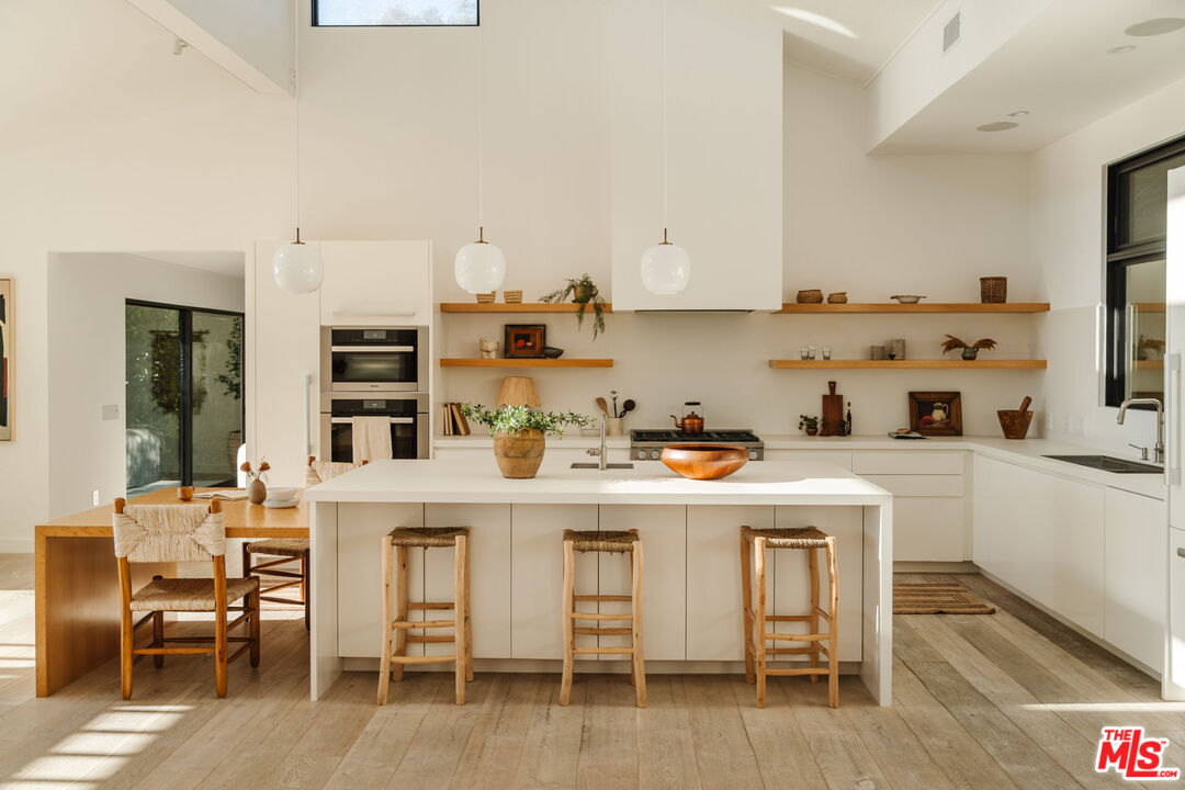 6767 Wandermere Road Malibu, CA 90265 - Photo 10 of 46 a kitchen with stainless steel appliances a table and chairs in it
