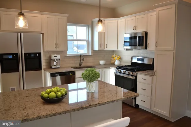 a kitchen with granite countertop a sink a stove and cabinets