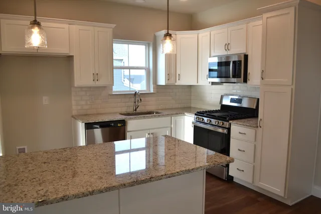 a kitchen with stainless steel appliances granite countertop a sink a stove and a microwave