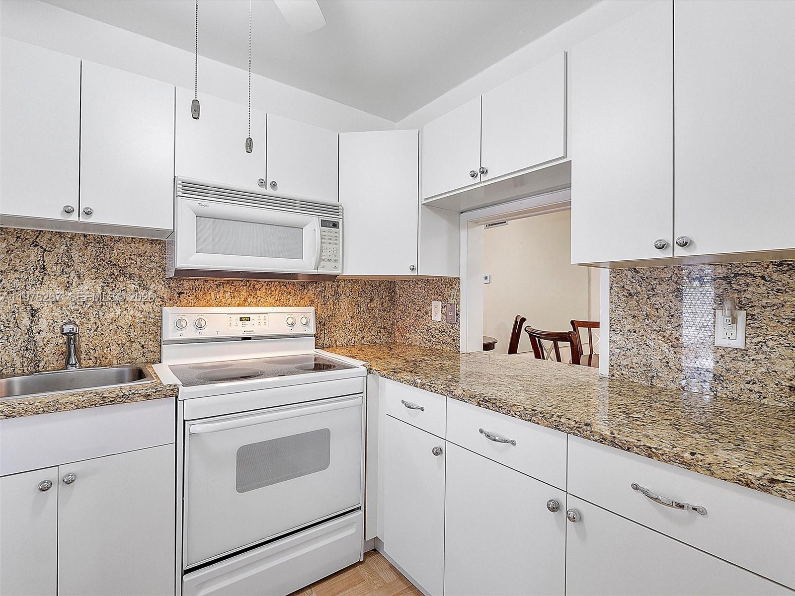 2050 Northeast 39th Street, Unit W212 Lighthouse Point, FL 33064 - Photo 3 of 17 a kitchen with granite countertop white cabinets and white appliances