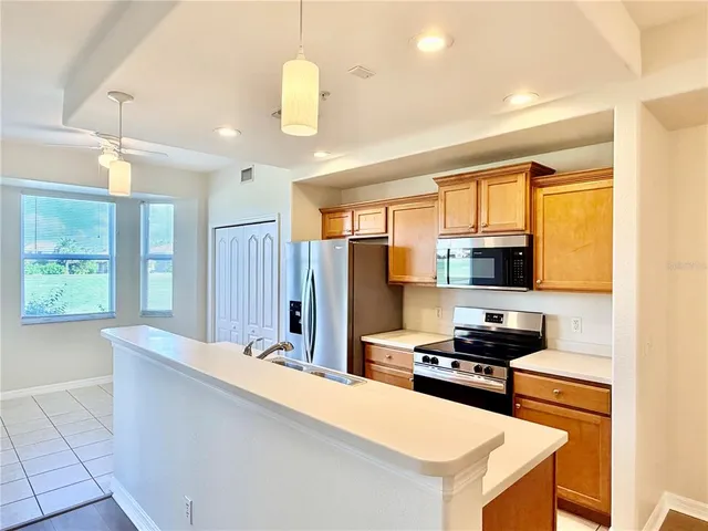 a kitchen with stainless steel appliances kitchen island granite countertop a stove refrigerator and cabinets