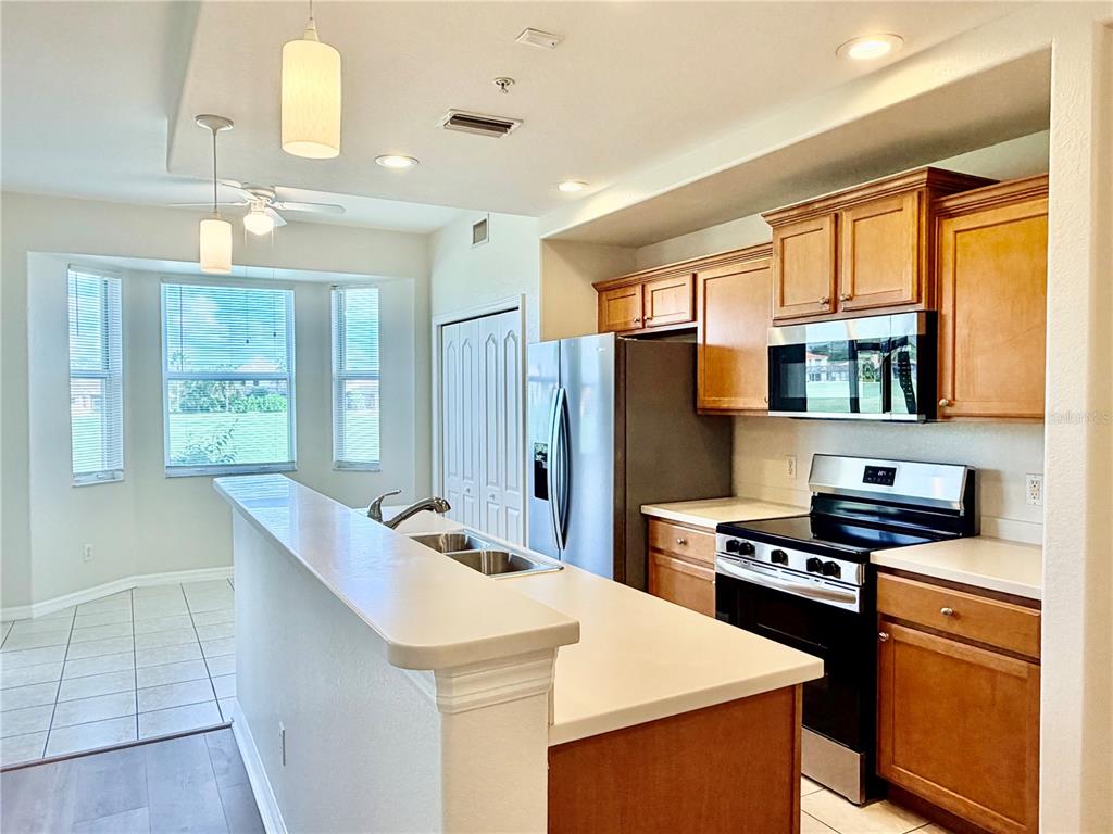 819 Fairwaycove Lane, Unit 102 Bradenton, FL 34212 - Photo 15 of 56 a kitchen with stainless steel appliances kitchen island granite countertop a stove refrigerator and cabinets