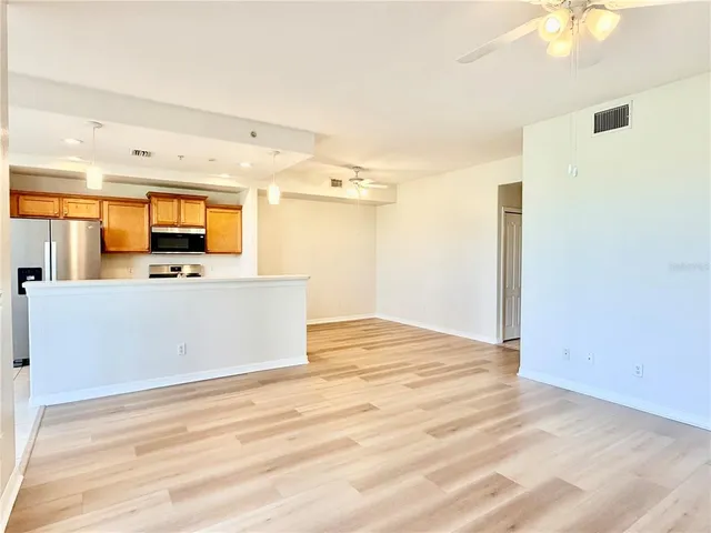 a view of a room with wooden floor and a ceiling fan
