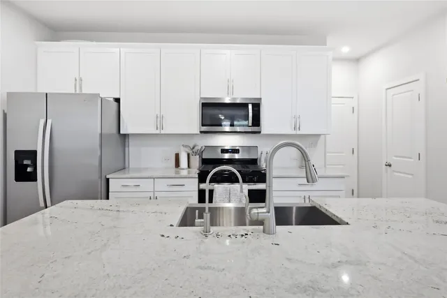 a kitchen with stainless steel appliances granite countertop a stove a refrigerator and a sink