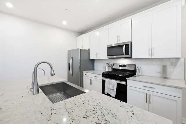 a kitchen with stainless steel appliances kitchen island granite countertop a stove top oven a sink a refrigerator with a dining table and chairs