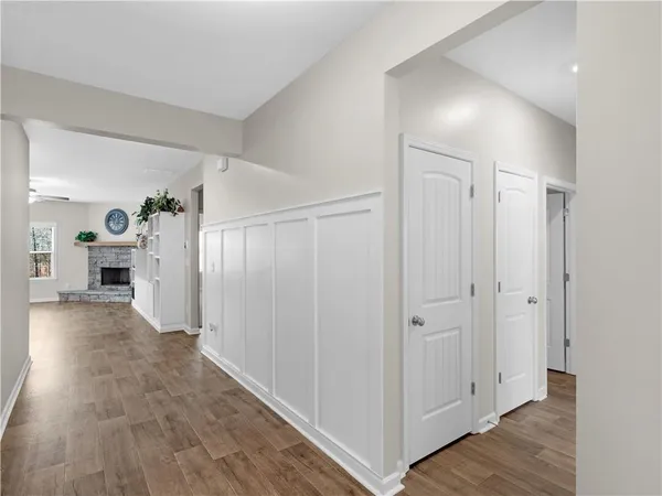 a view of a hallway with wooden floor closet and bathroom