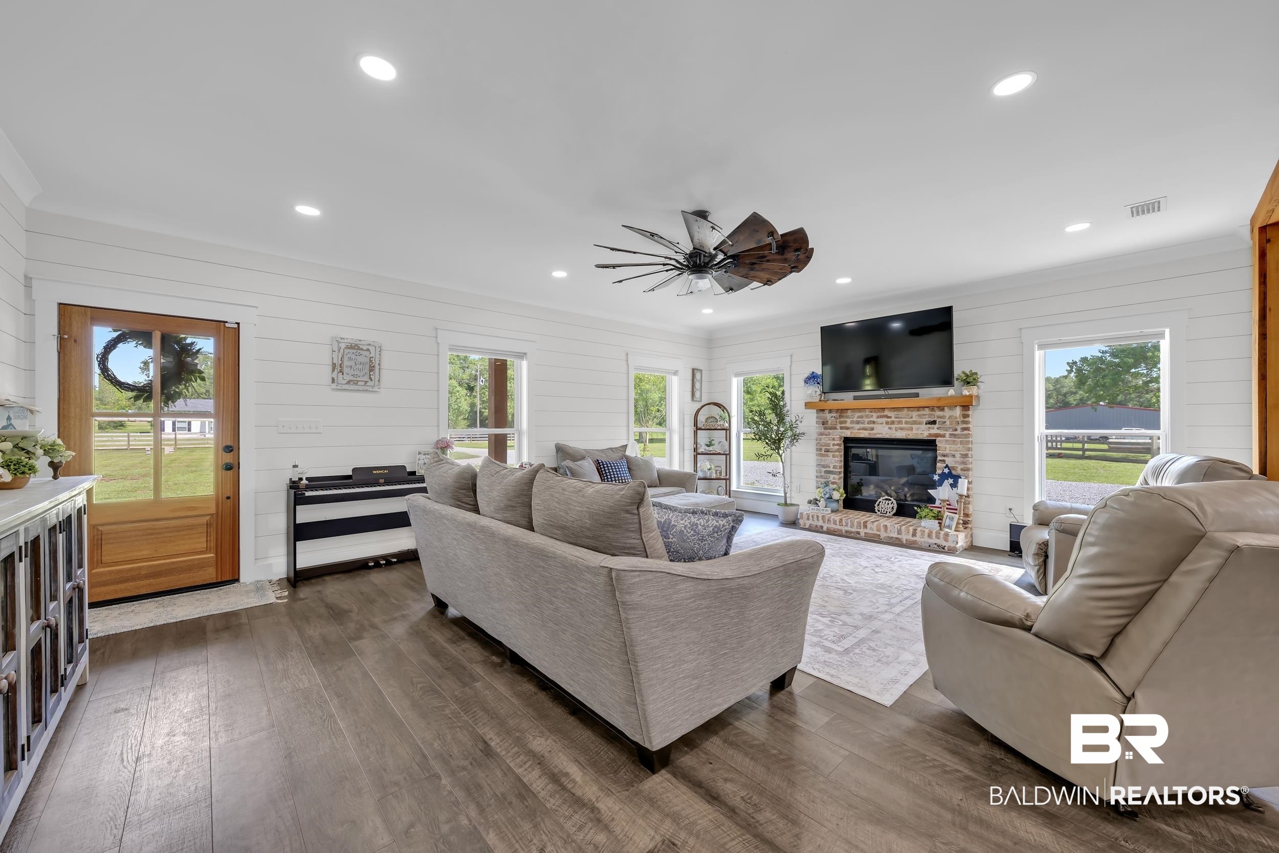 6576 Ranch Loop Road East Grand Bay, AL 36541 - Photo 10 of 39 Spacious living area featuring wood-finish flooring, white shiplap walls, a brick fireplace with a wood mantel, recessed lighting, and an overhead fan