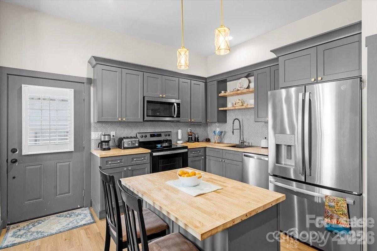 8478 Rocky River Road, Unit 1 Harrisburg, NC 28075 - Photo 2 of 8 a kitchen with stainless steel appliances granite countertop a refrigerator a stove a sink a dining table and chairs with wooden floor