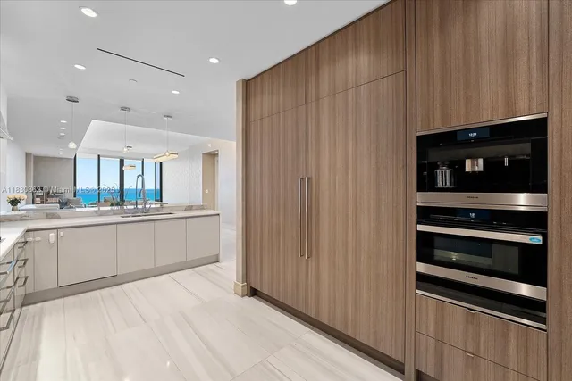 a large white kitchen with a sink and dishwasher a stove top oven with wooden floor