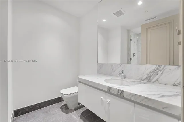 a bathroom with a granite countertop sink a toilet and a mirror