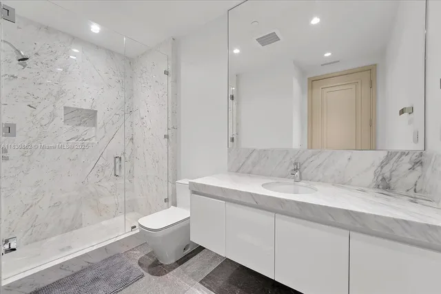 a bathroom with a granite countertop sink a toilet and shower