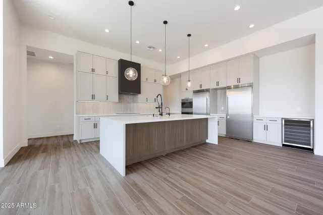 a large kitchen with stainless steel appliances kitchen island a large counter space a sink wooden floor and cabinets