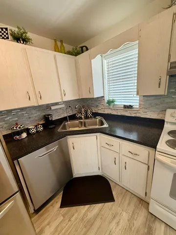 a kitchen with a sink a stove and white cabinets