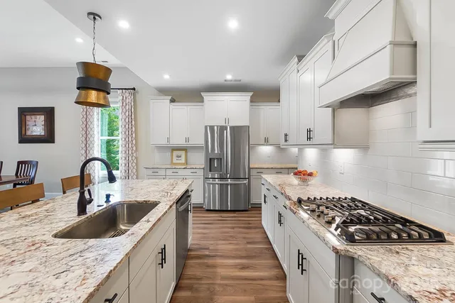 a kitchen with stainless steel appliances granite countertop a sink stove and refrigerator