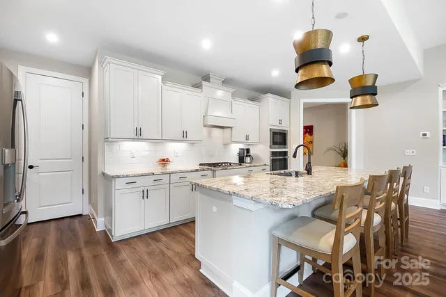 a kitchen with stainless steel appliances granite countertop a sink a stove and a refrigerator