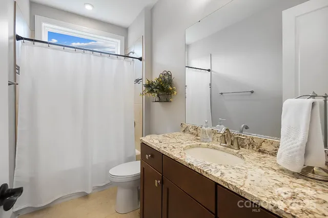 a bathroom with a granite countertop sink toilet and shower