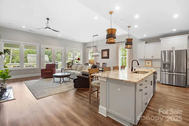 a kitchen with stainless steel appliances granite countertop a refrigerator a sink dishwasher a oven and a dining table with wooden floor