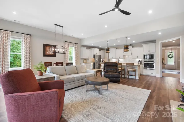 a living room with furniture kitchen view and a wooden floor