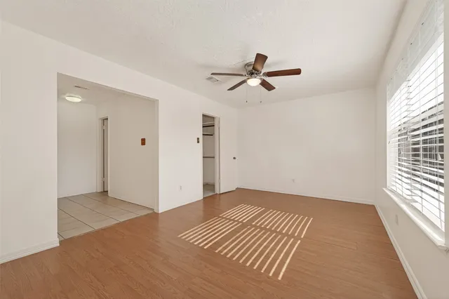 a view of empty room with wooden floor and fan