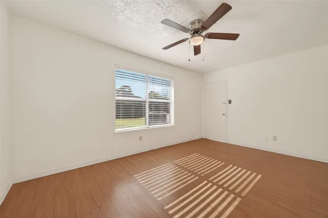 an empty room with a window and ceiling fan