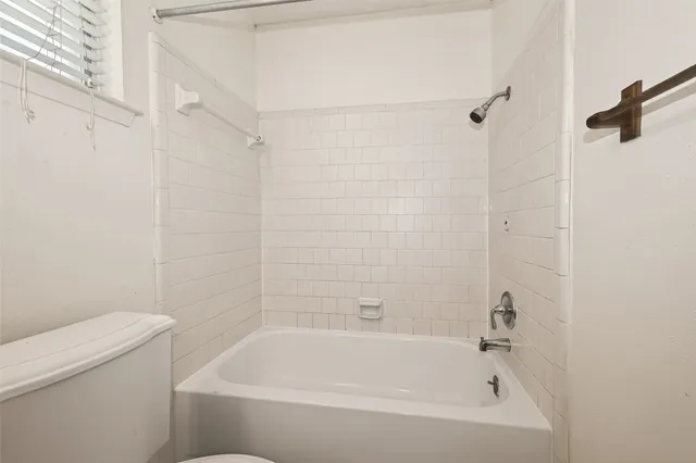 a white bath tub sitting next to a white toilet and a shower