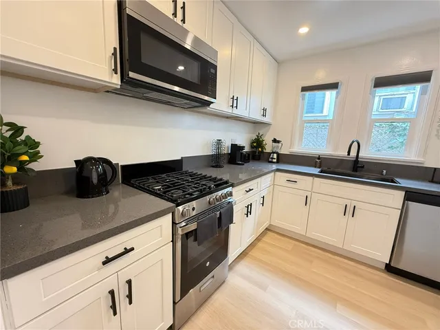 a white kitchen with granite countertop stainless steel appliances stove and sink